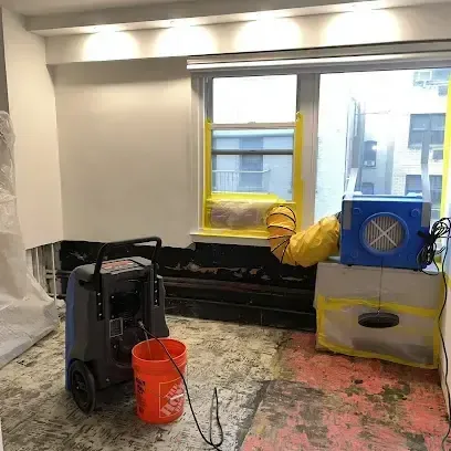 A dehumidifier and an air mover running together in a room where the flooring has been taken out for drying