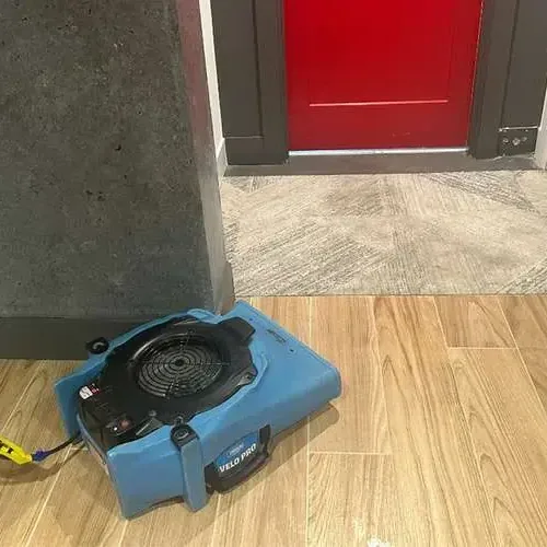 An air mover blowing across a wood-look tile floor near an open doorway