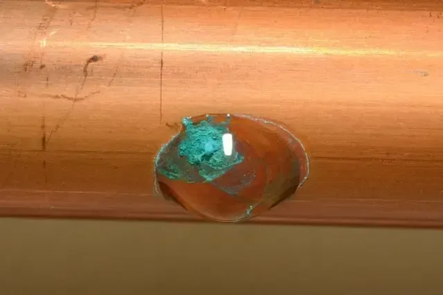 Green corrosion around a pinhole opening in a copper supply pipe