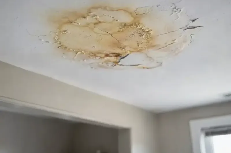 Cracked, water-stained ceiling below a leak in an apartment