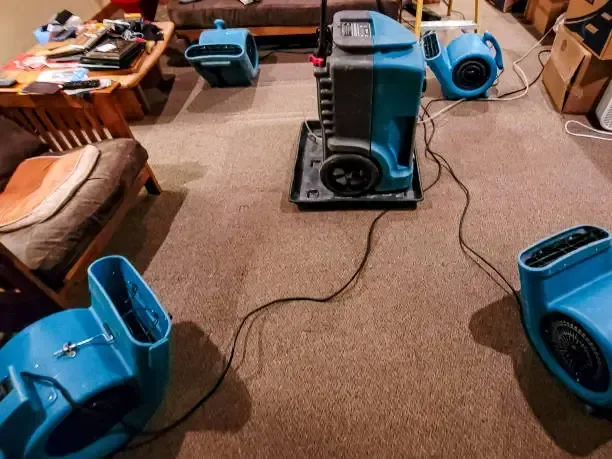 Air movers and a dehumidifier running in a room during drying